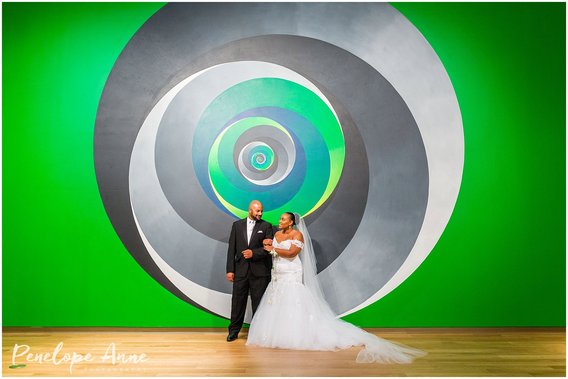 bride and groom in front of art